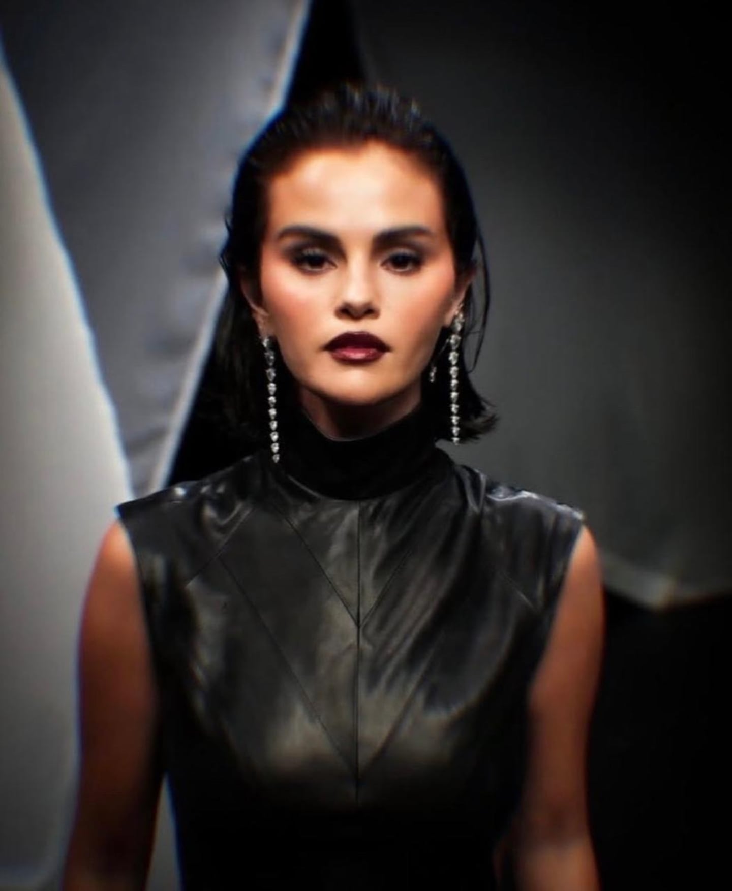 Modelo luciendo un vestido de cuero negro en una pasarela de moda