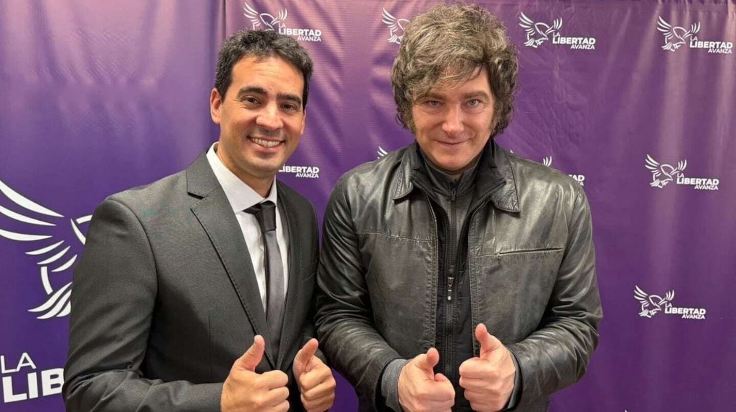 Adrián Ravier y Javier Milei posando con pulgares arriba en un evento