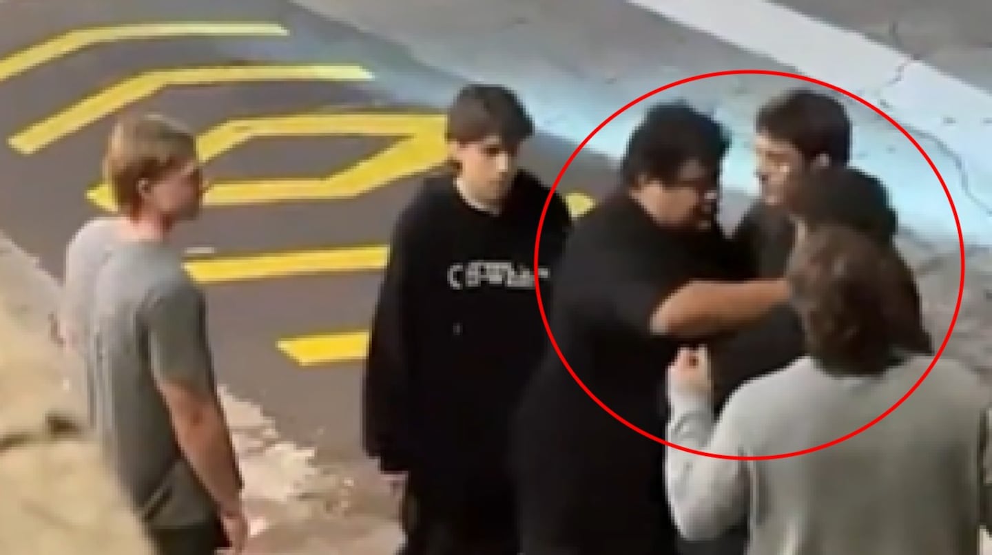 Grupo de jóvenes en la calle, uno de ellos en el centro parece estar en una discusión