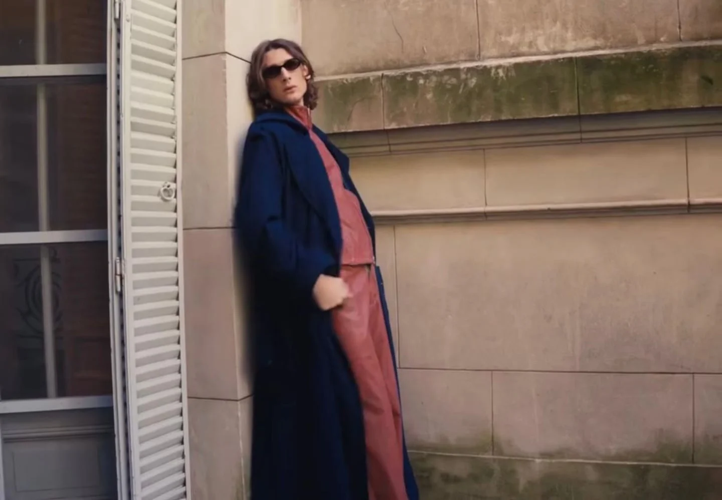 Ángelo Mutti Spinetta posando con un abrigo azul y gafas de sol en un entorno urbano