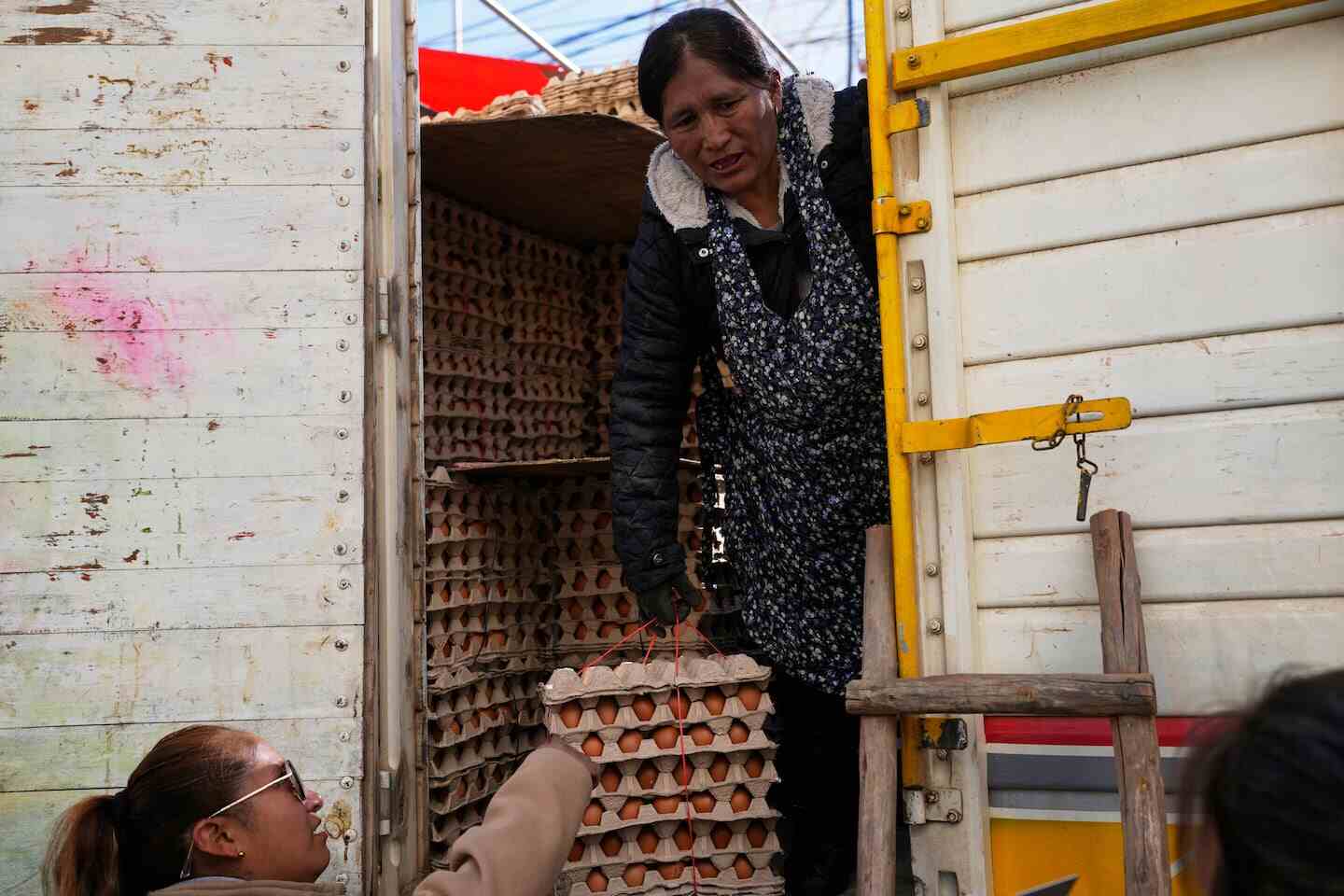 Mujer entregando cajas de huevos desde un camión en Bolivia