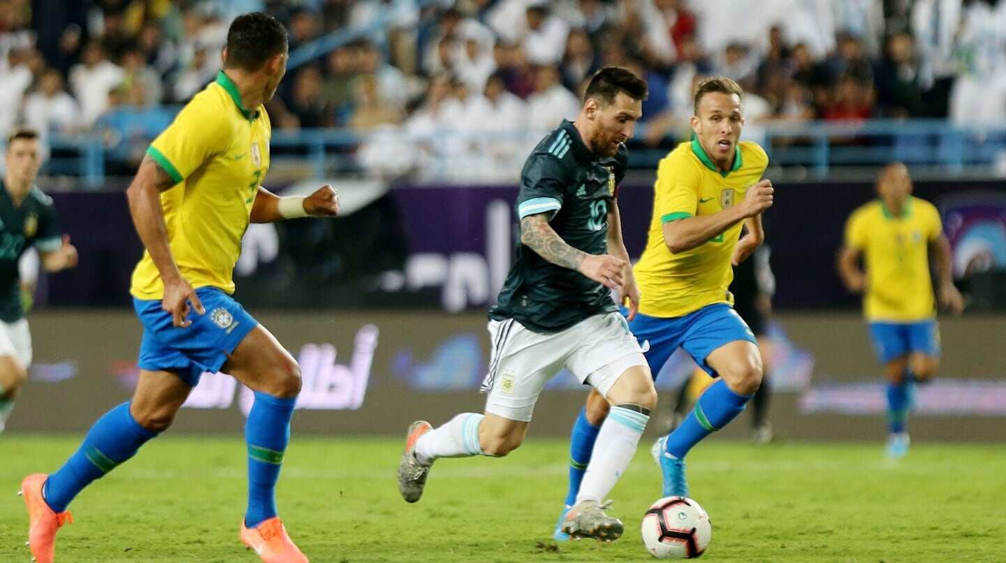 Lionel Messi driblando entre jugadores de Brasil durante un partido de fútbol