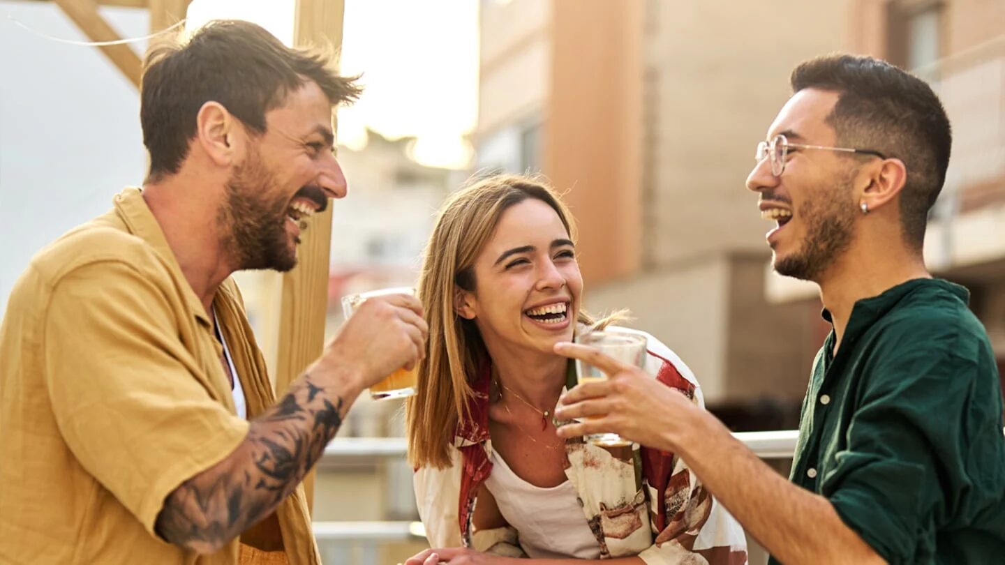 Tres amigos riendo y disfrutando de una conversación en una terraza