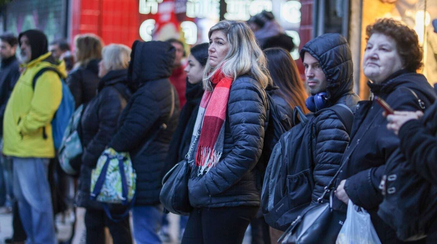 Grupo de personas esperando en la calle, algunas con abrigos y bufandas