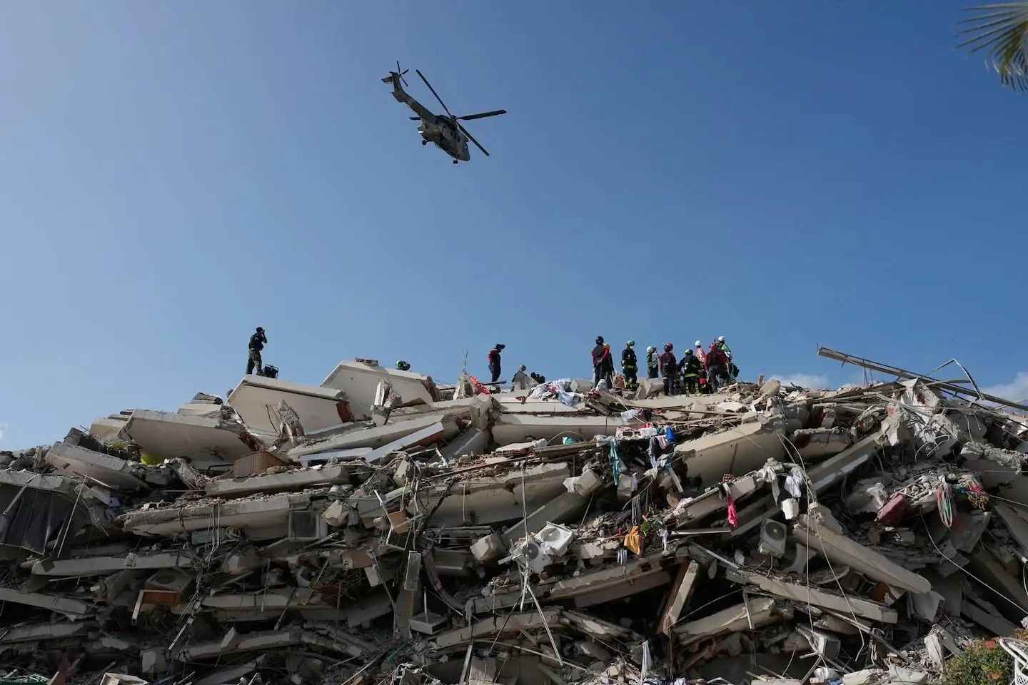Rescatistas trabajan entre escombros tras un terremoto en Venezuela, con un helicóptero sobrevolando la zona