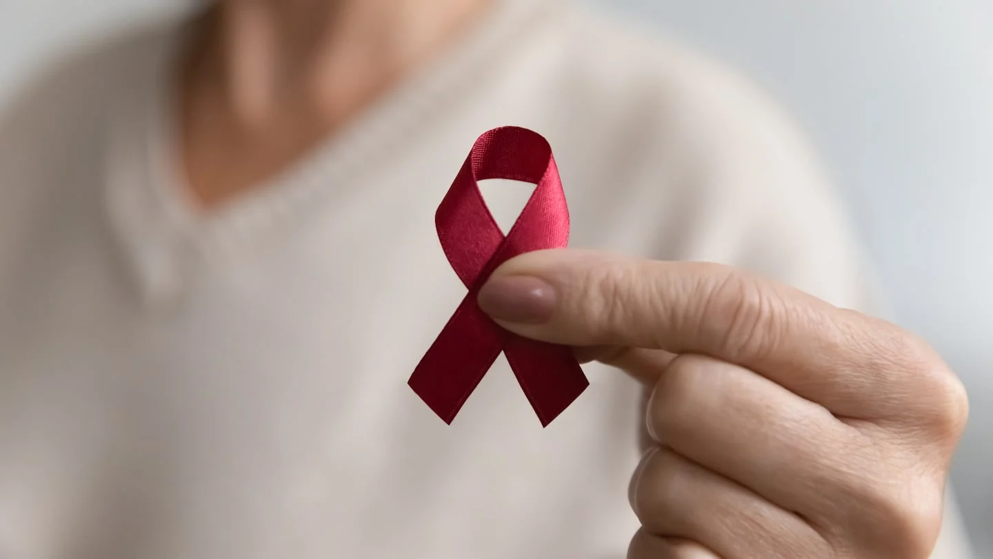 Persona sosteniendo un lazo rojo en apoyo a la concienciación sobre el VIH