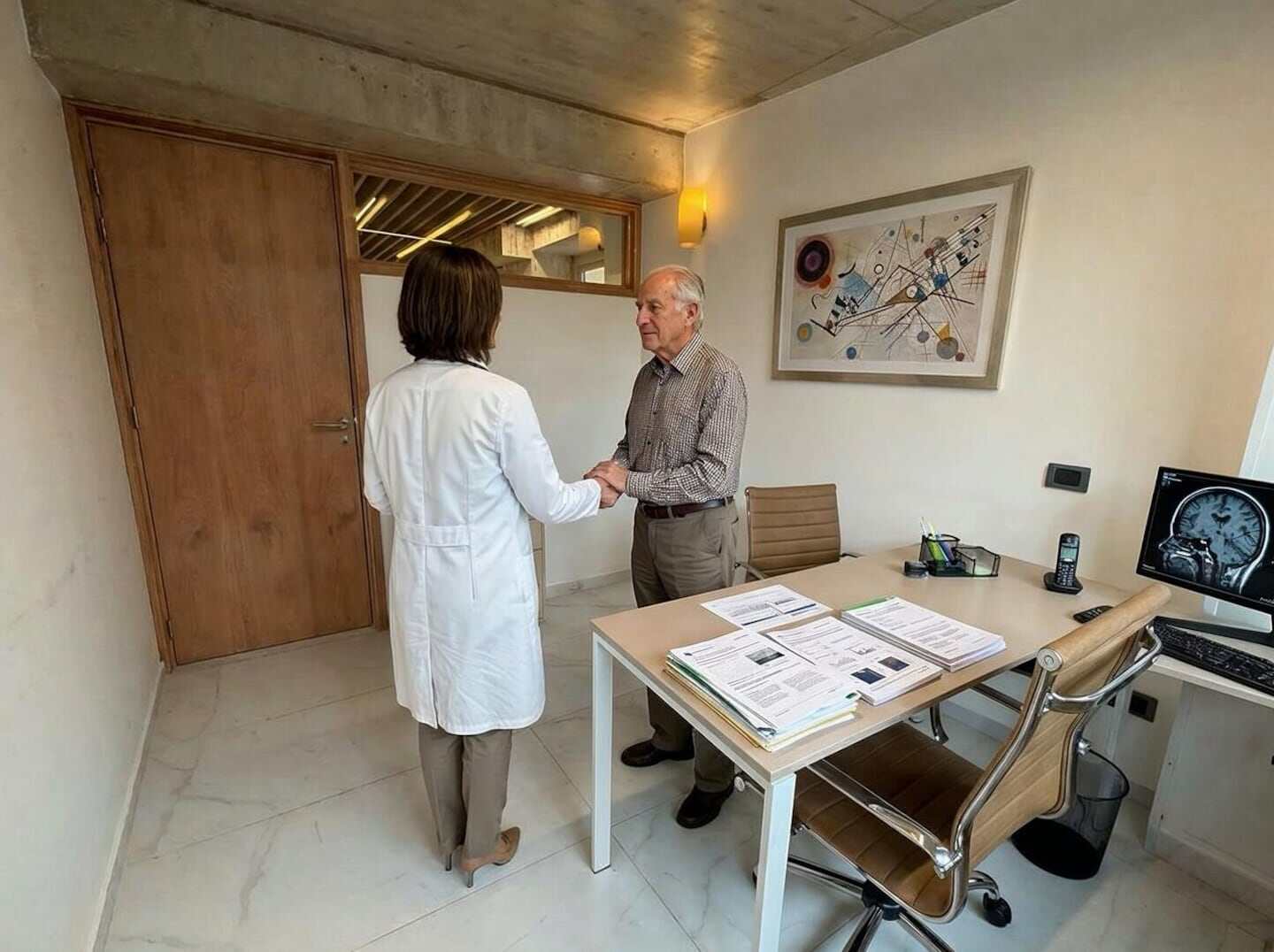 Médico y paciente anciano estrechando manos en una consulta médica