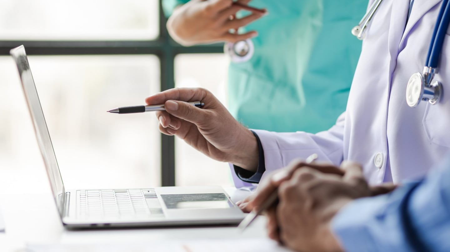 Médico revisando información en una computadora portátil en un entorno clínico
