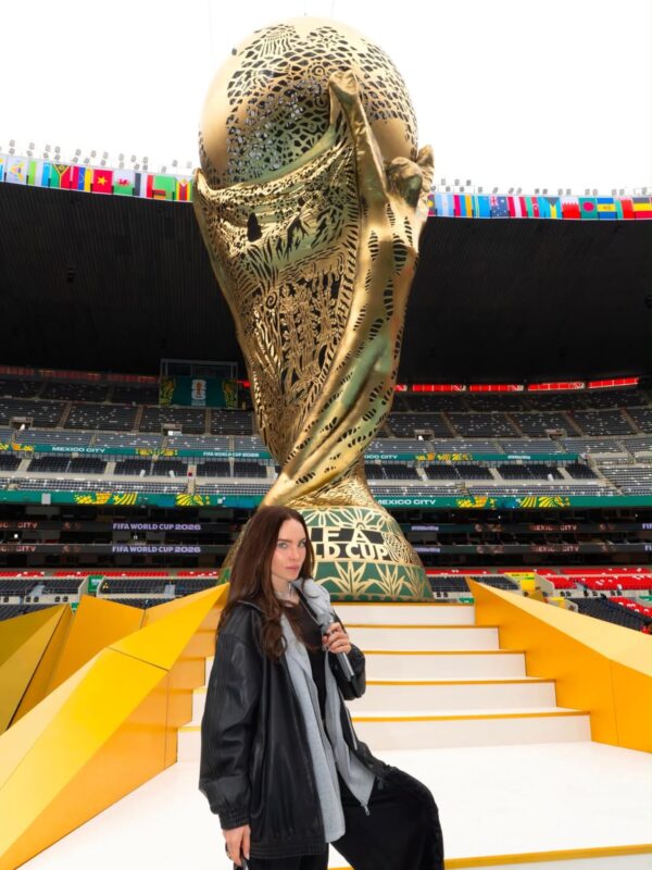 Belinda posando frente al trofeo de la Copa Mundial de la FIFA en un estadio