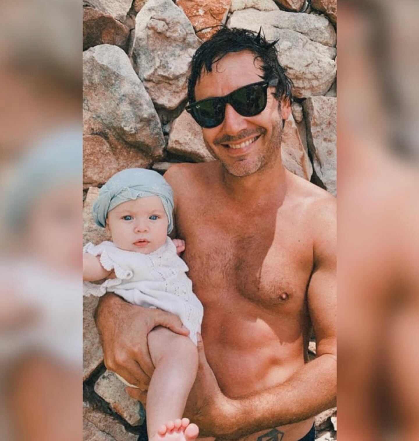 Benjamín Vicuña sosteniendo a su bebé en la playa con gafas de sol