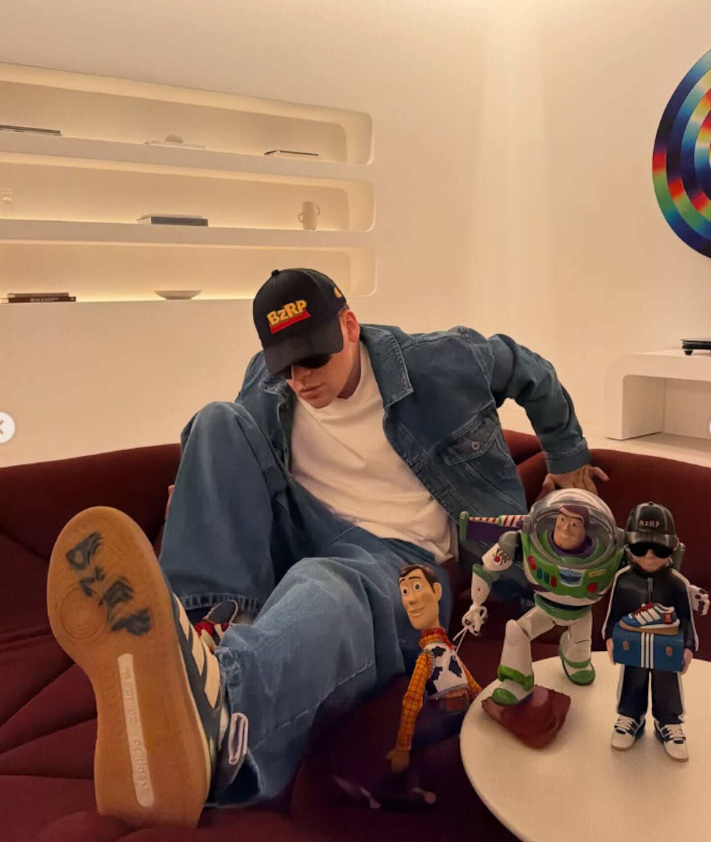 Bizarrap sentado en un sofá con juguetes de Buzz Lightyear y Woody