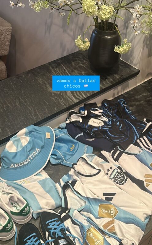 Ropa y accesorios de la selección argentina dispuestos sobre una mesa con flores de fondo