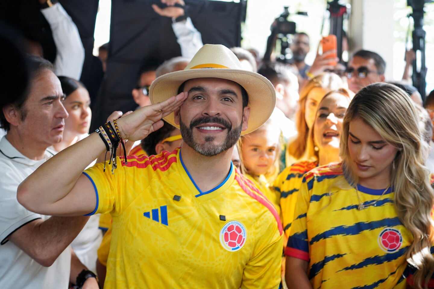Hombre con sombrero saluda mientras viste camiseta de la selección colombiana en un ambiente festivo