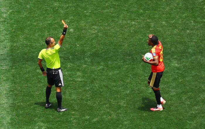 Árbitro mostrando tarjeta amarilla a un jugador durante un partido de fútbol