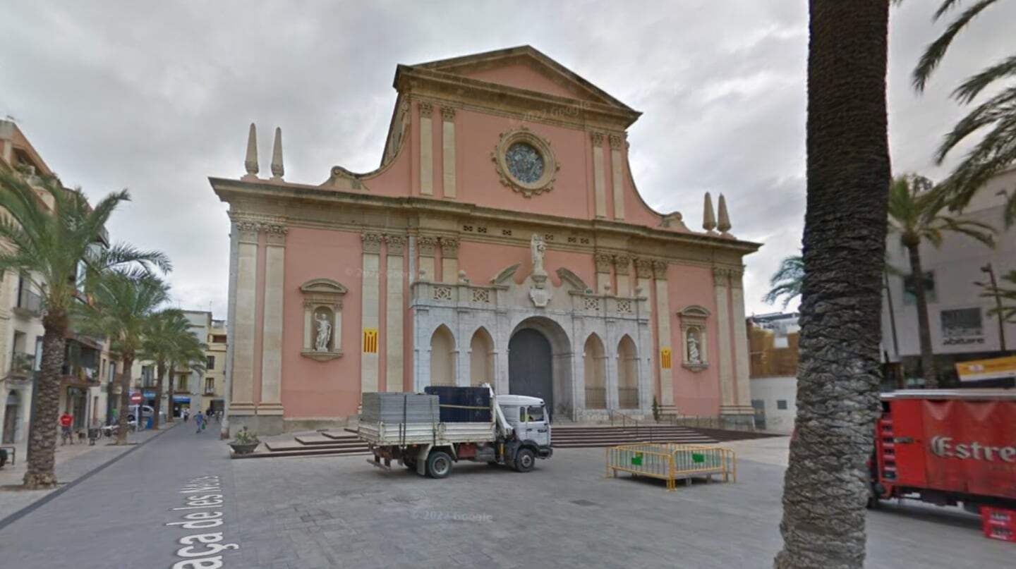 Iglesia en una plaza de España con un camión de carga estacionado frente a ella