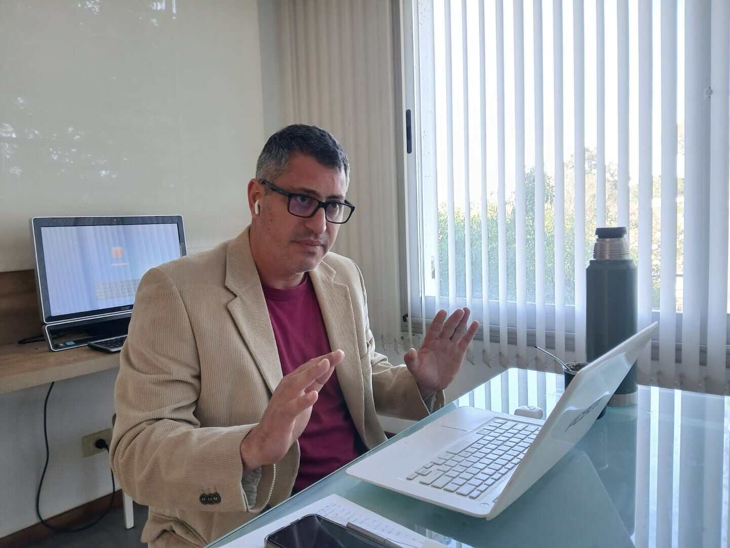 Hombre en oficina con laptop y auriculares, discutiendo sobre el conflicto laboral en Sudamericana de Lácteos