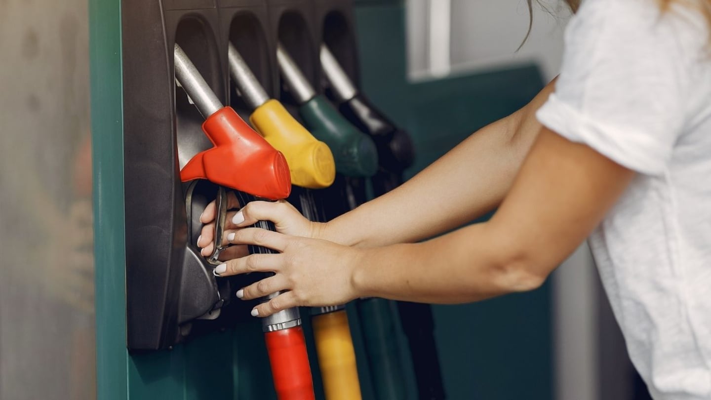 Persona utilizando una bomba de combustible en una gasolinera