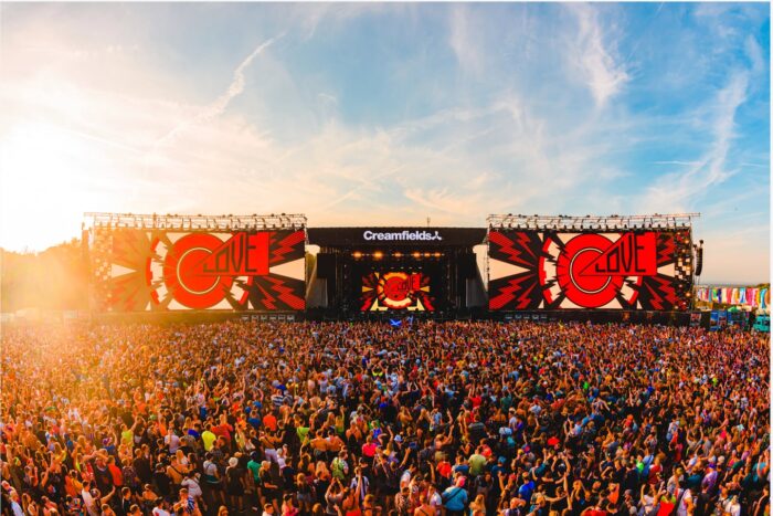 Multitud disfrutando del festival Creamfields Argentina con pantallas gigantes y un atardecer colorido