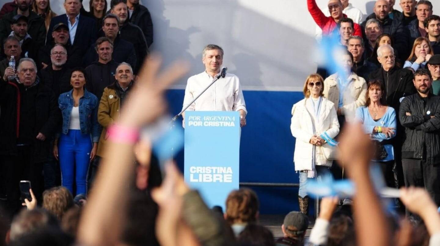 Un orador en un acto político con una multitud de seguidores en el fondo