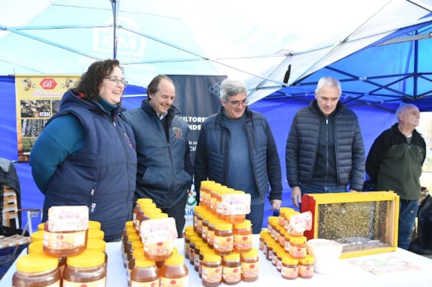 Cuatro personas observan productos de apicultura en un evento en Buenos Aires