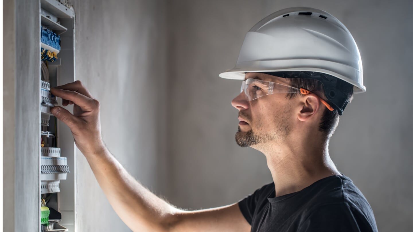 Electricista trabajando en un panel eléctrico con casco y gafas de seguridad