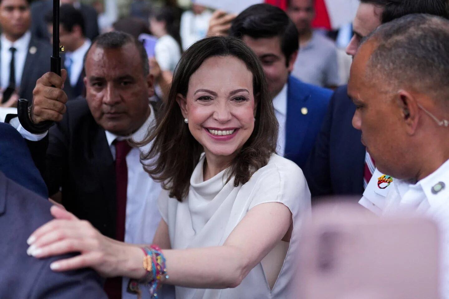 Delcy Rodríguez sonriendo mientras es rodeada por un grupo de personas en un evento público