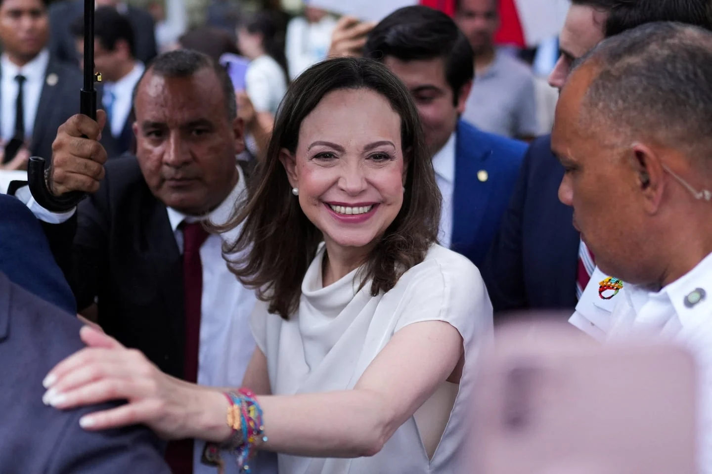 Delcy Rodríguez sonriendo mientras es rodeada por un grupo de personas en un evento público
