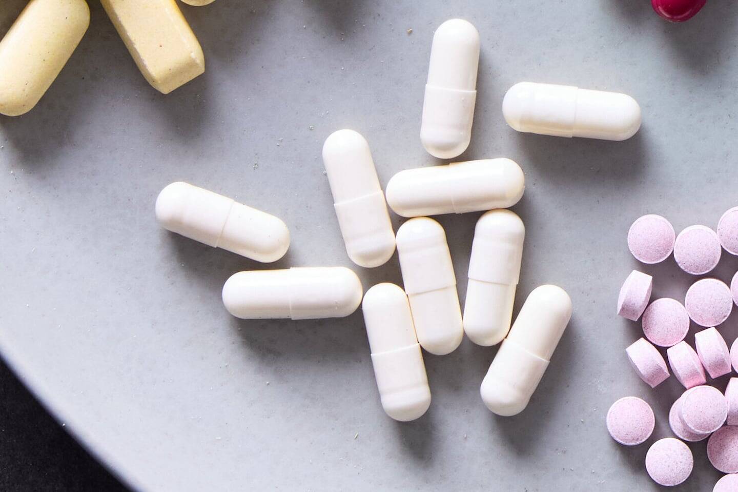 Suplementos en forma de cápsulas y tabletas sobre una superficie gris