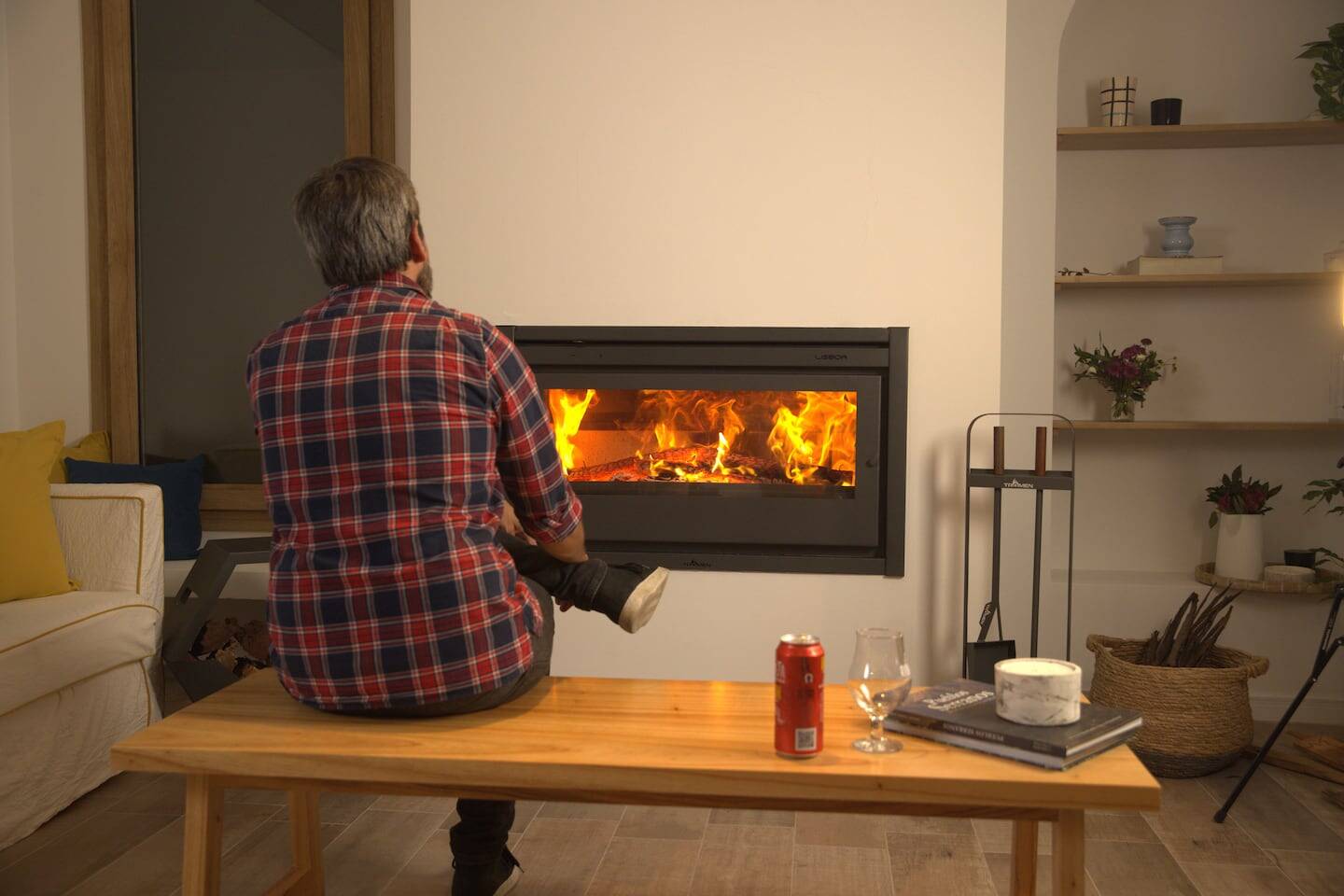 Hombre sentado en un banco frente a una chimenea con fuego