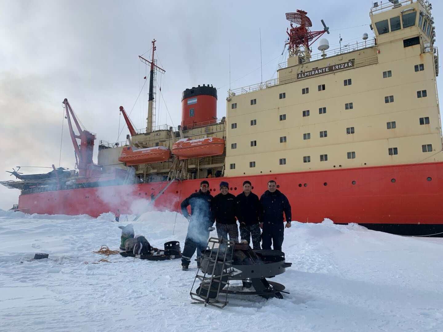 Grupo de personas cocinando con parrillas Tromen en un entorno nevado junto a un barco
