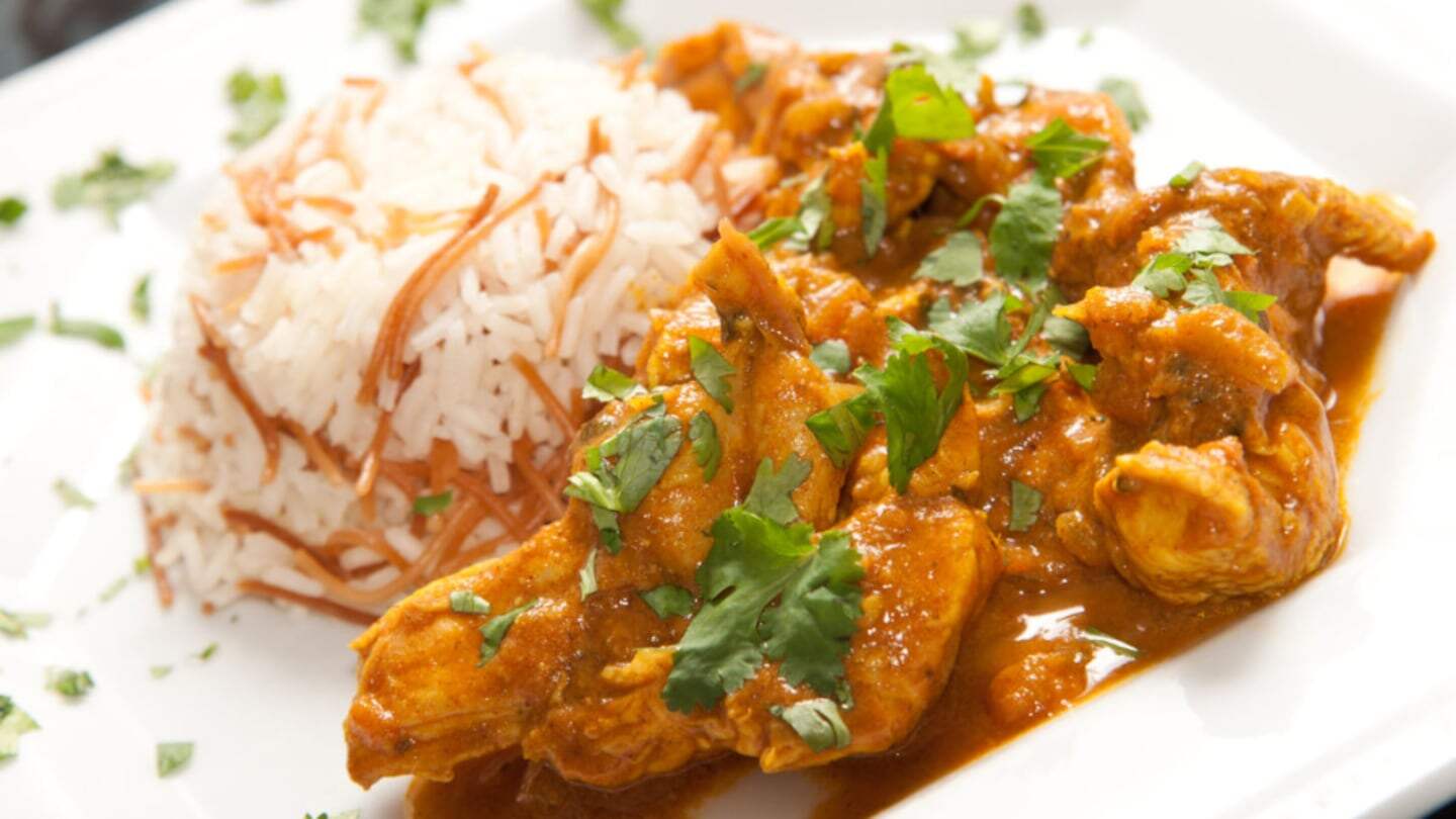 Plato de pollo tikka masala servido con arroz y cilantro fresco