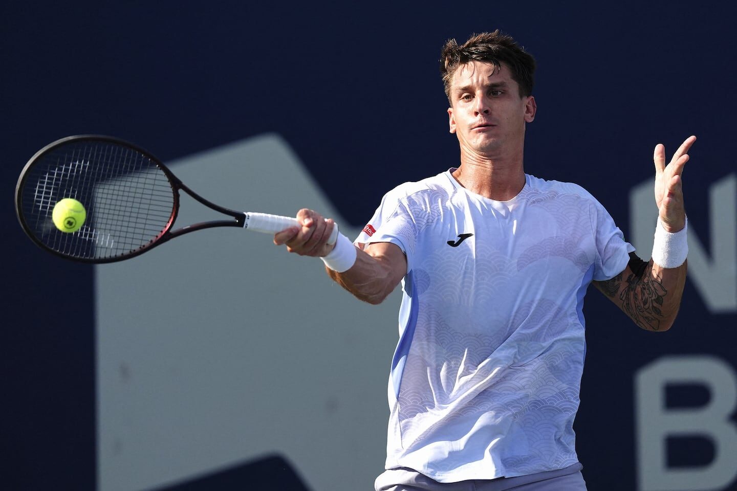 Sebastián Báez golpeando la pelota durante un partido en Wimbledon