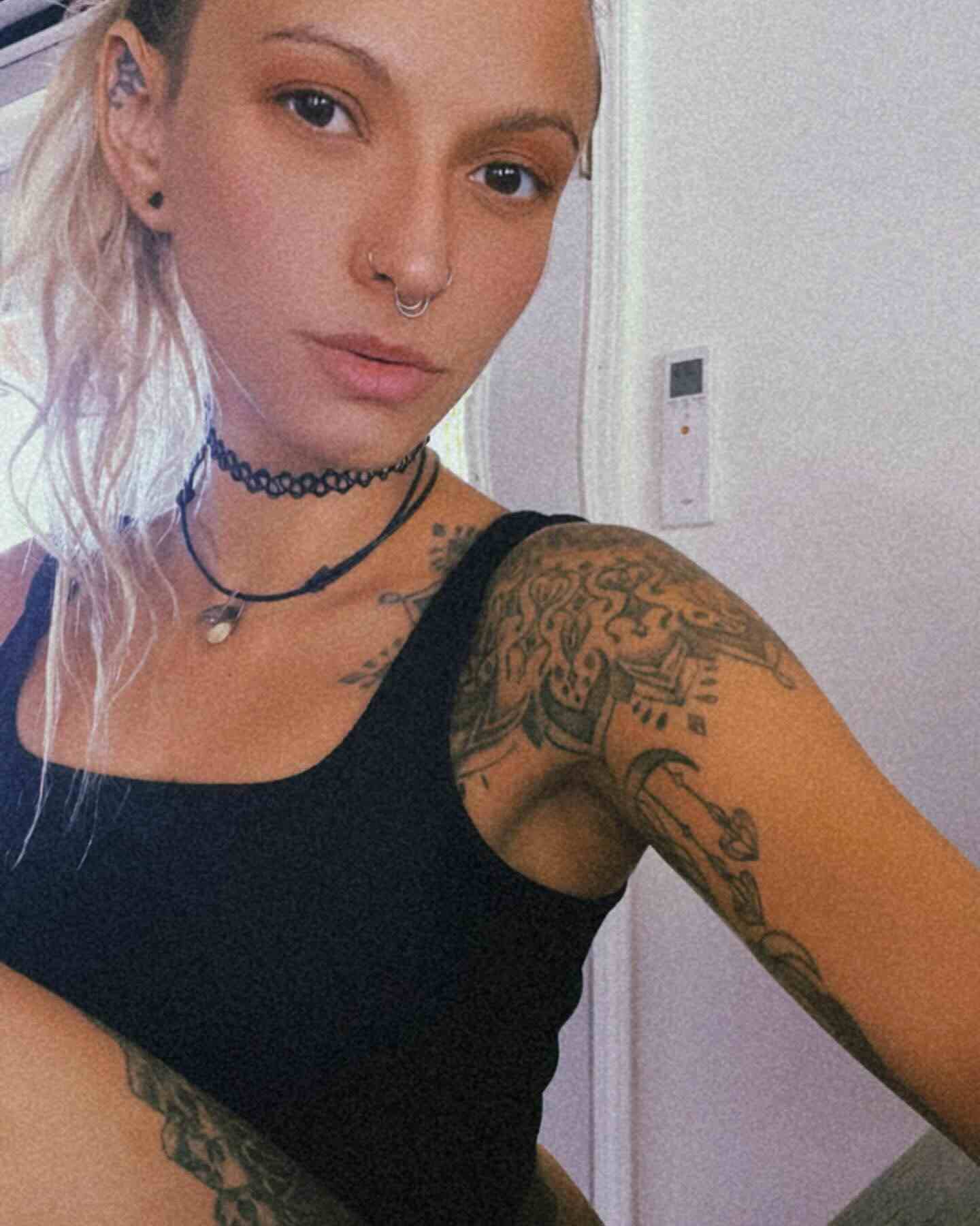 Mujer con tatuajes y peinado recogido en un entorno interior