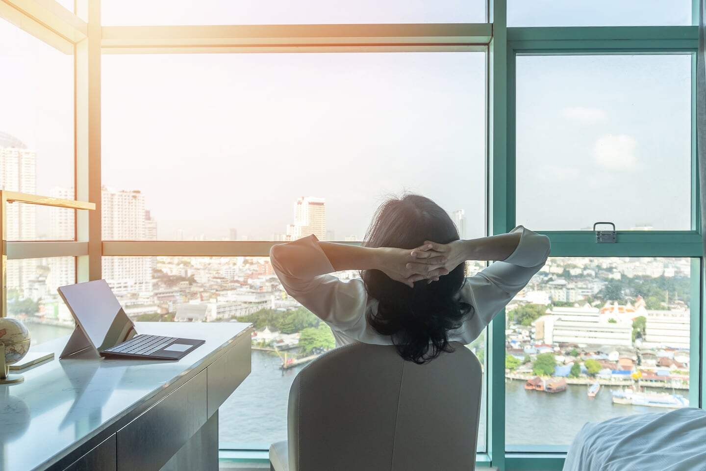 Mujer sentada frente a una ventana con vista a la ciudad, reflexionando sobre el sedentarismo