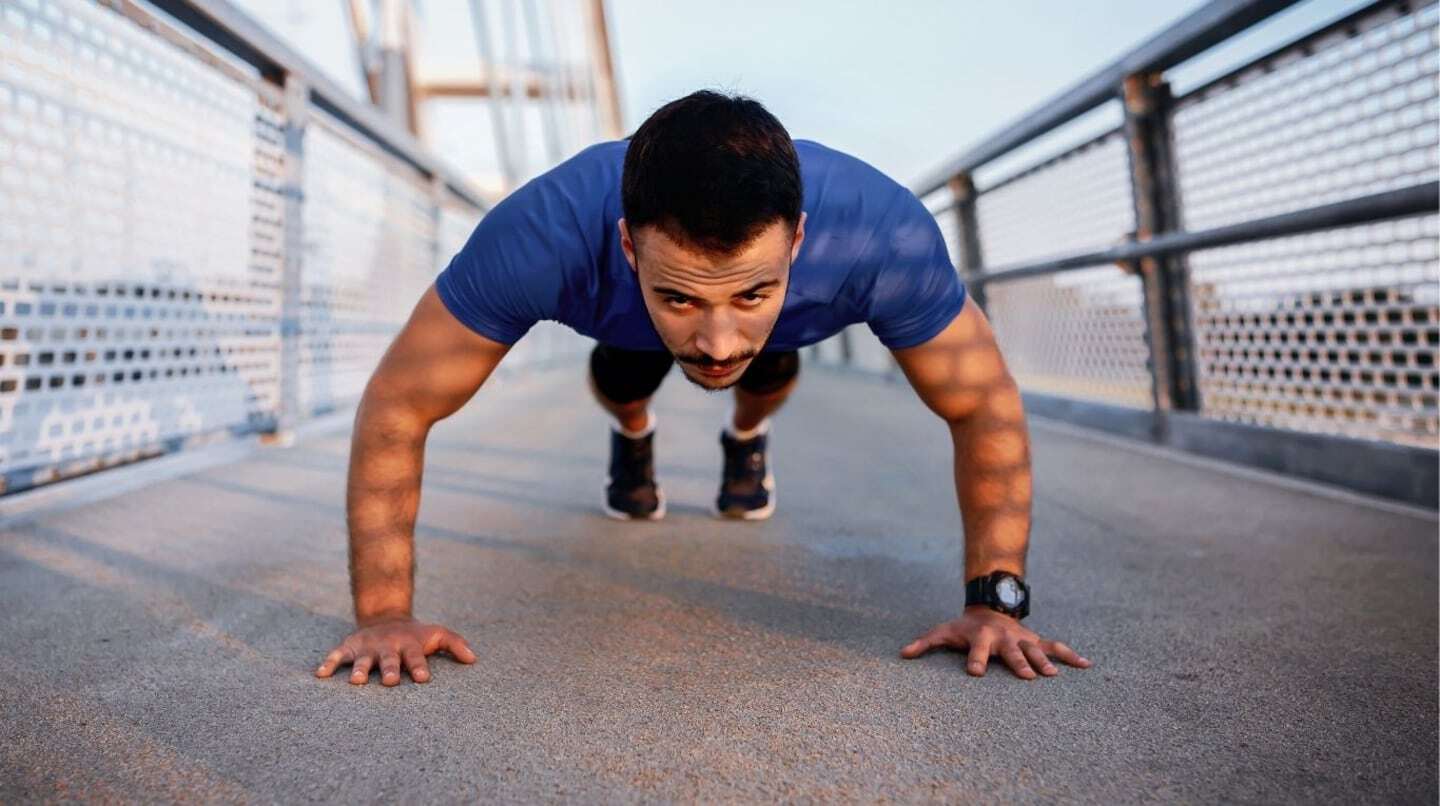 Hombre realizando flexiones en un puente al aire libre