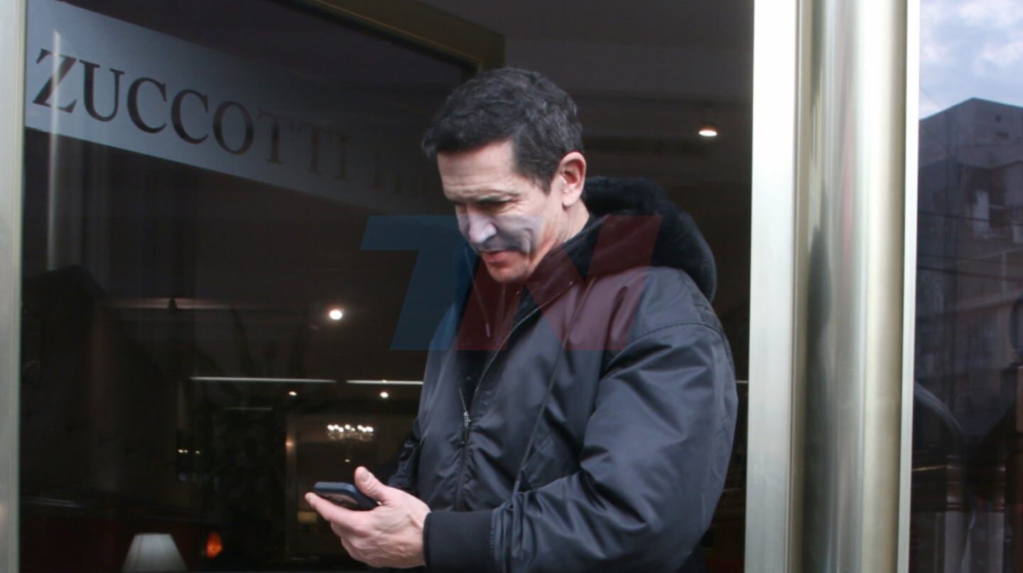 Diego Ramos revisando su teléfono frente a la entrada del Teatro Zuccotti