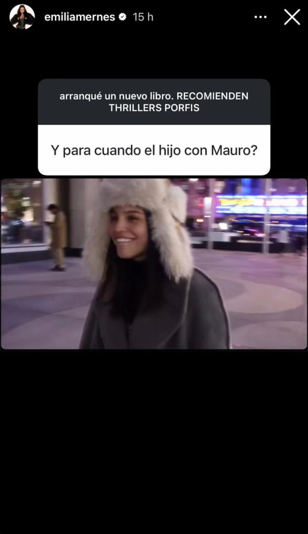 Emilia Mernes sonríe mientras lleva un abrigo y un gorro de piel en un entorno urbano