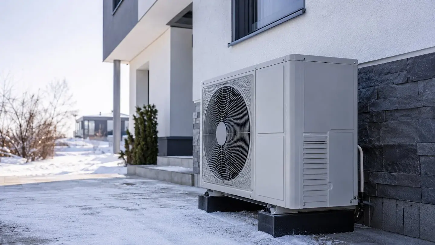 Unidad exterior de aerotermia instalada en una vivienda en invierno