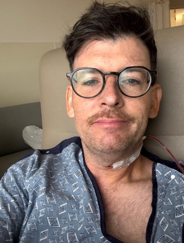 Moshe Kasher en una cama de hospital mostrando su cicatriz tras la operación de cáncer de amígdalas