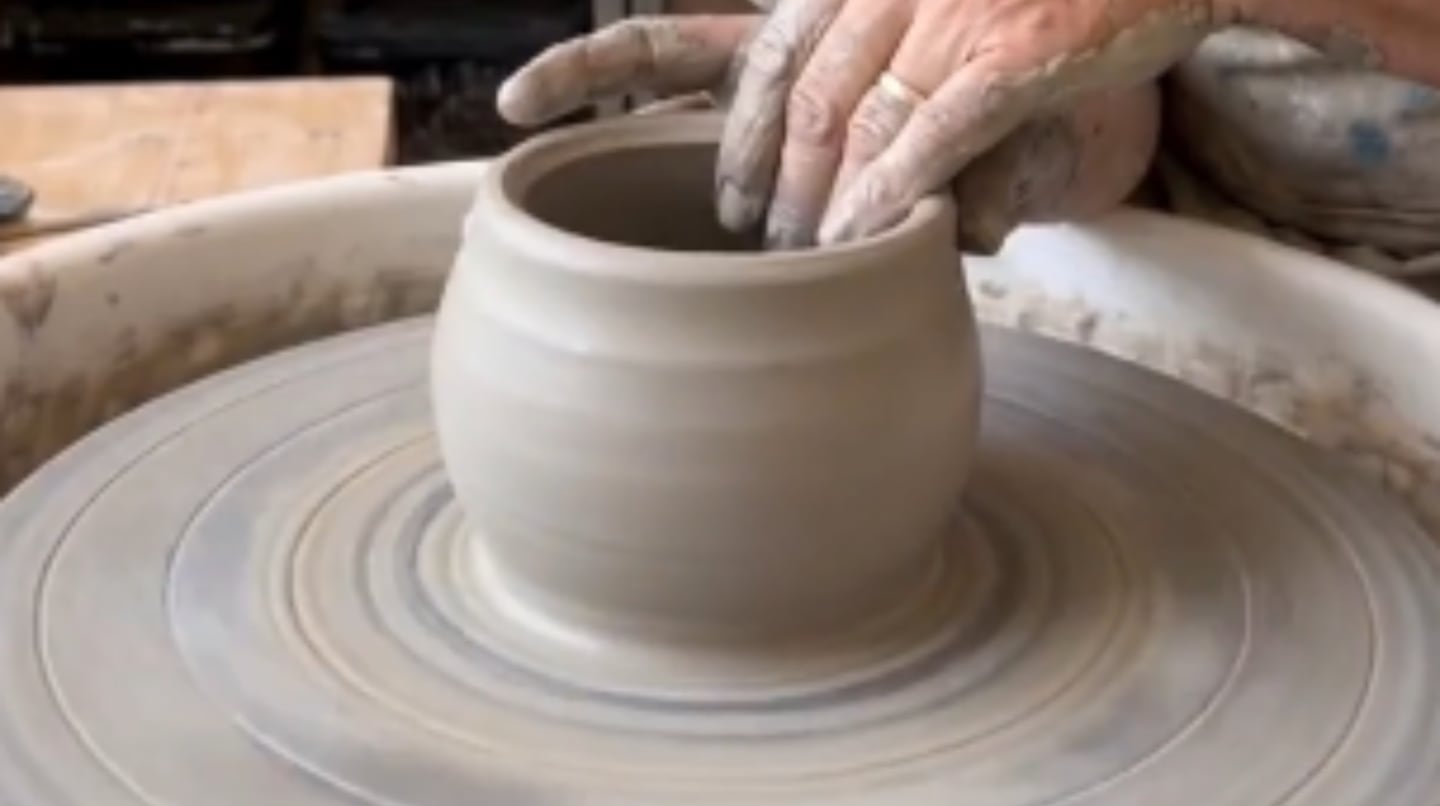 Artesano modelando una taza de cerámica en un torno