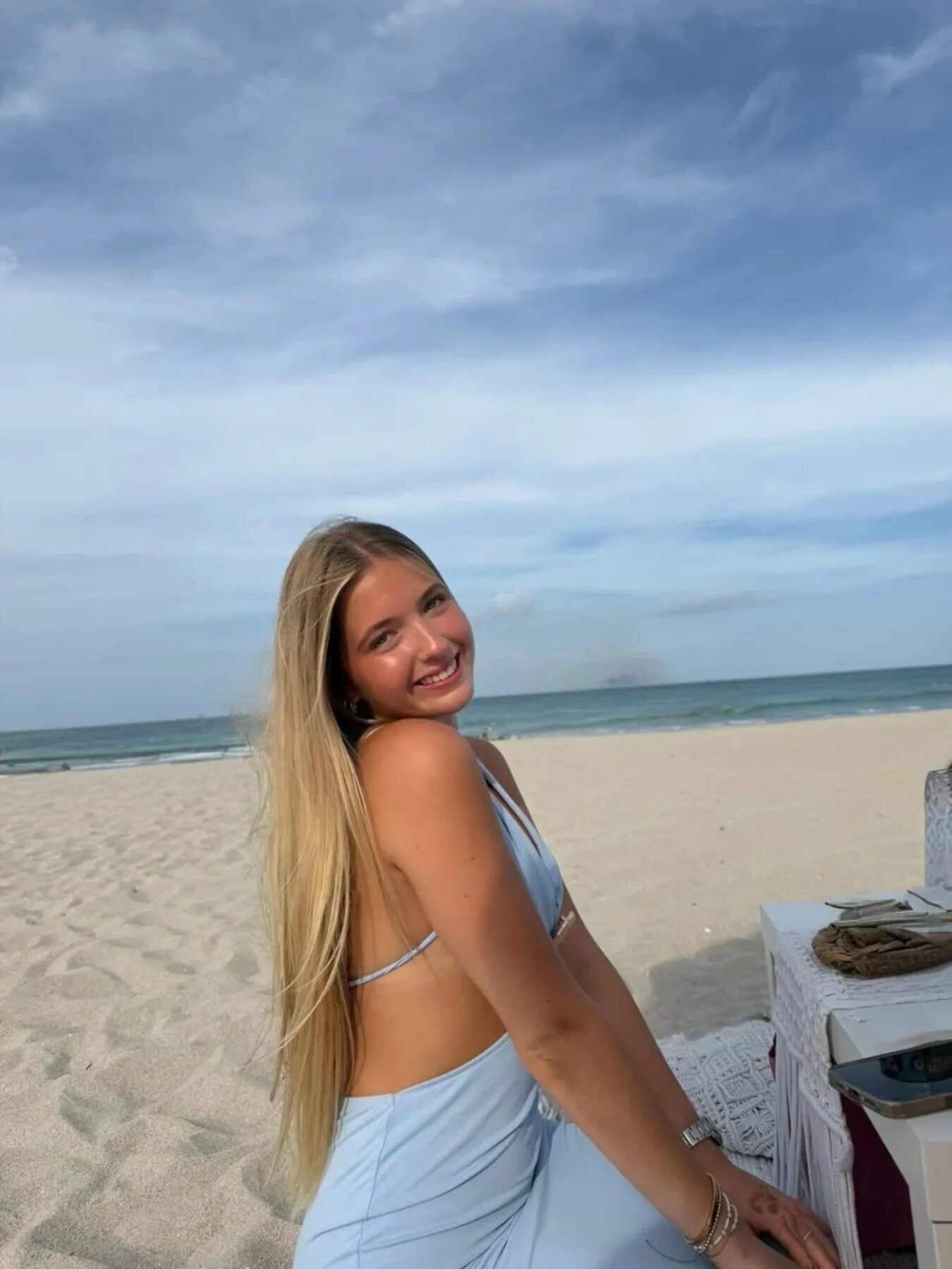 Joven sonriente con vestido baby blue en la playa