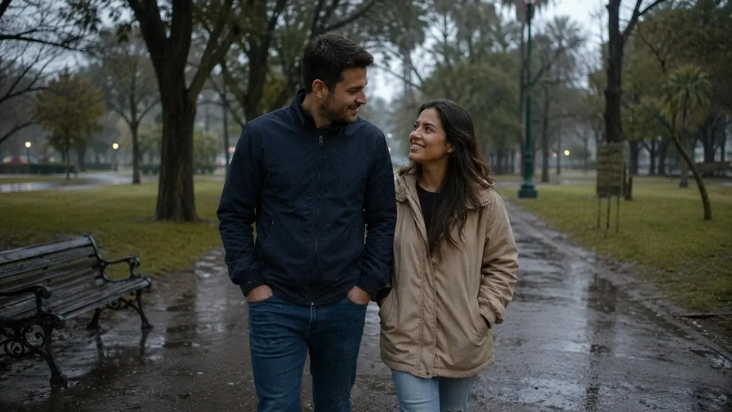 Damián y Carolina caminando juntos por un parque en un día lluvioso