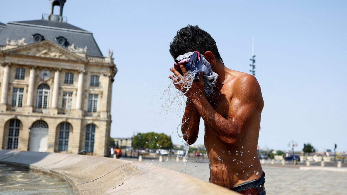Hombre refrescándose en una fuente durante una ola de calor en una ciudad europea