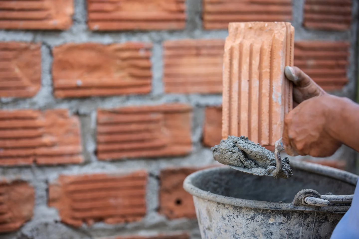 Trabajador de la construcción colocando ladrillos en una pared de mampostería