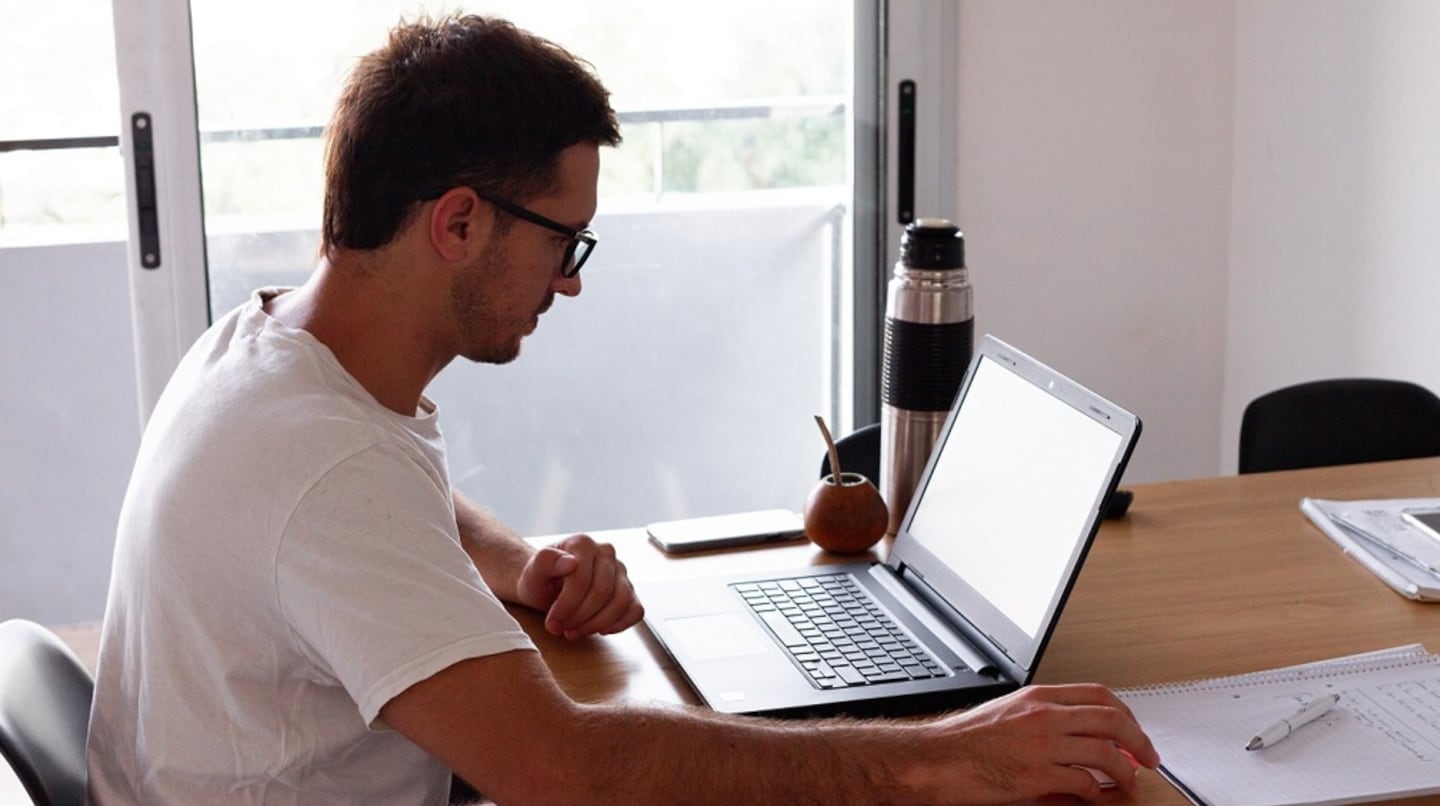 Hombre trabajando en una laptop en una mesa de trabajo