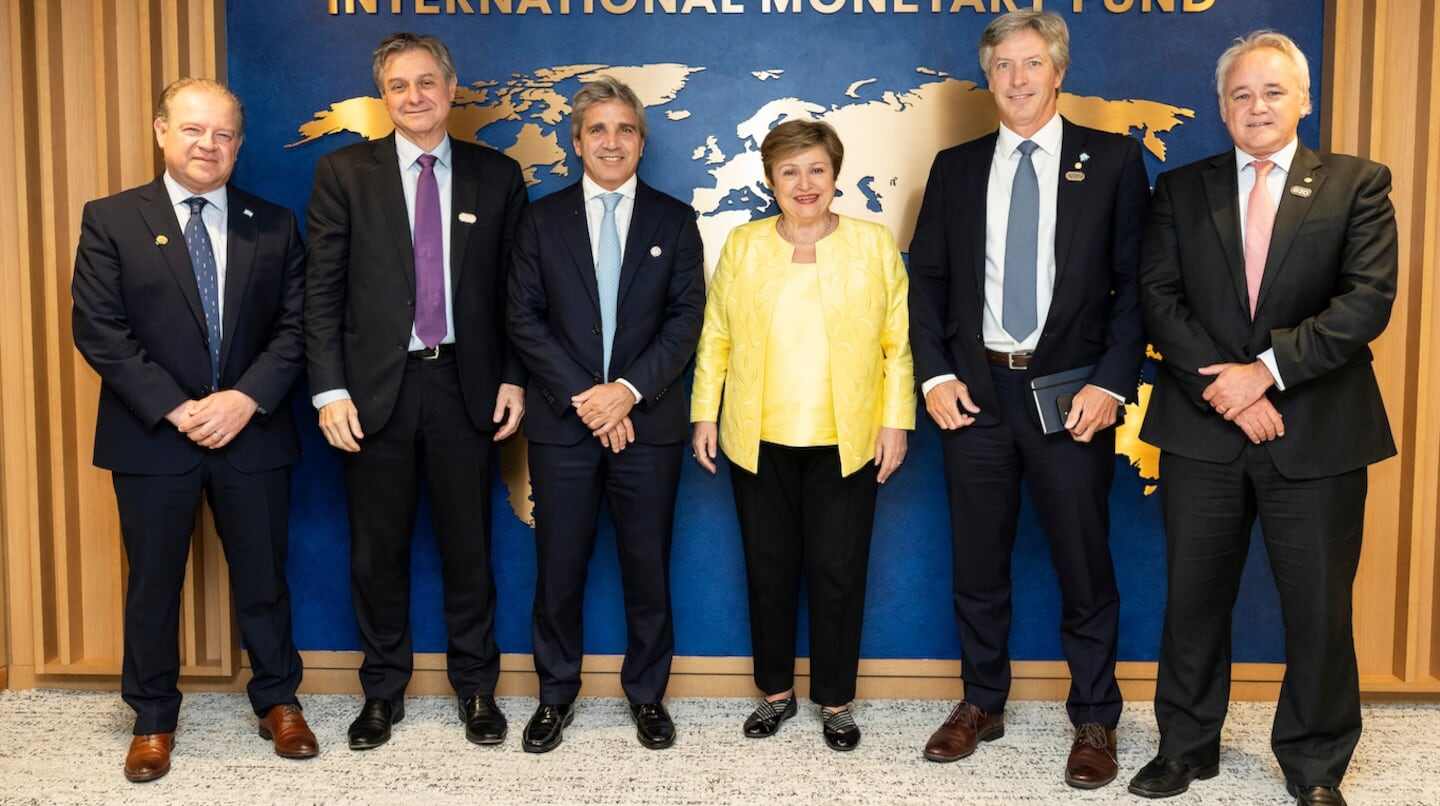 Funcionarios del FMI posando frente al logo del Fondo Monetario Internacional