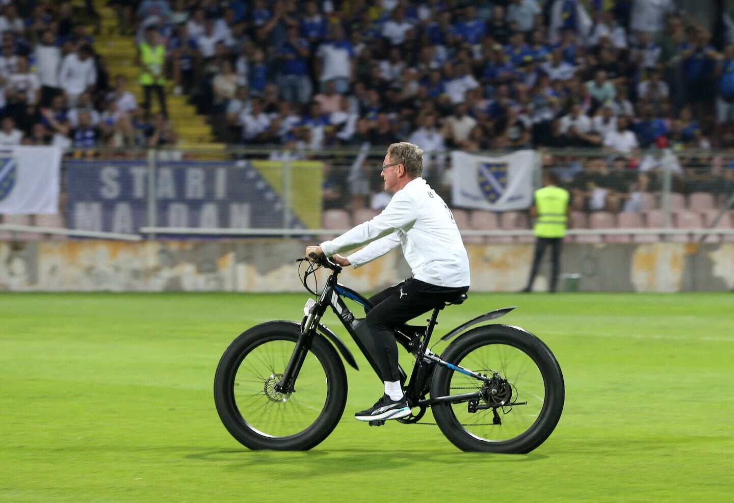 Entrenador Ralf Rangnick montando una bicicleta en el campo de fútbol