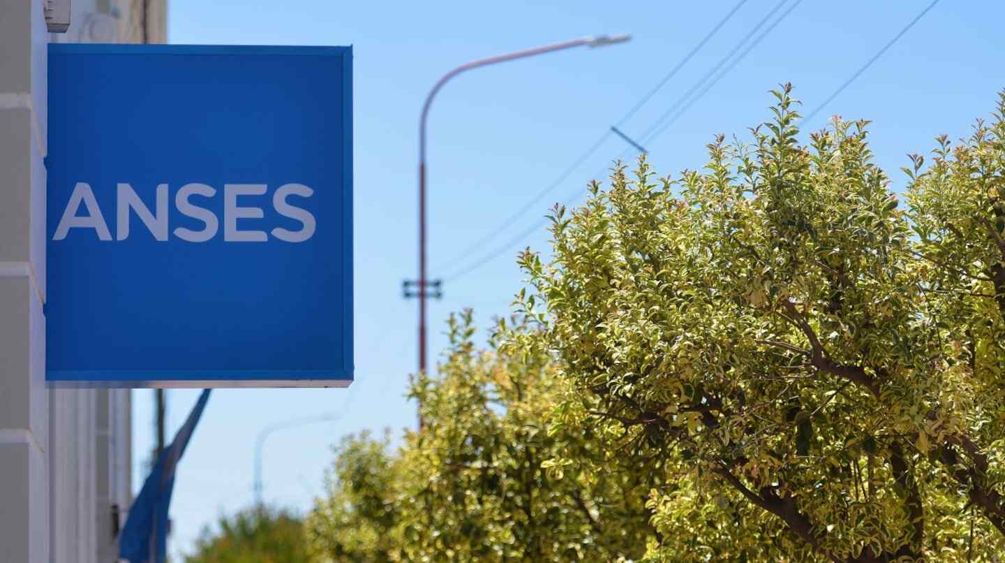 Cartel de ANSES en una oficina con árboles al fondo
