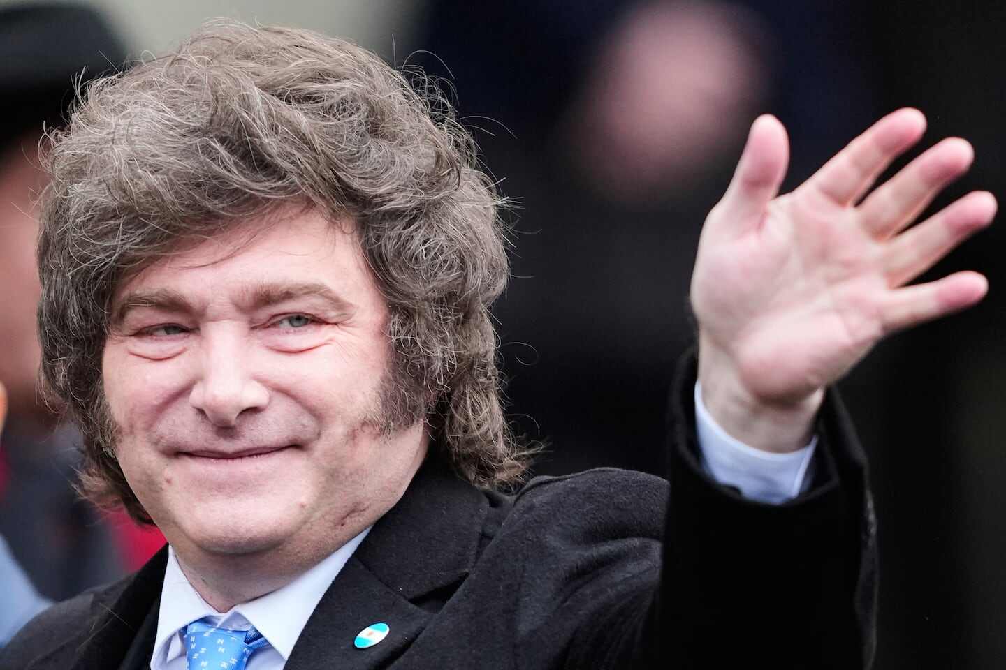 Manuel Adorni saludando con una mano en un evento público