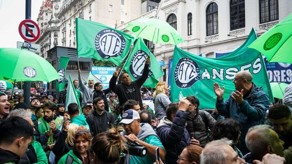 Manifestantes con banderas y paraguas verdes en una protesta por aumento salarial en la ciudad